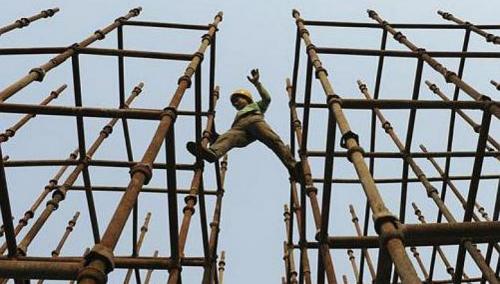 Safety and working conditions in China are in question as a laborer walks between scaffolding at a highway construction project in the Anhui province