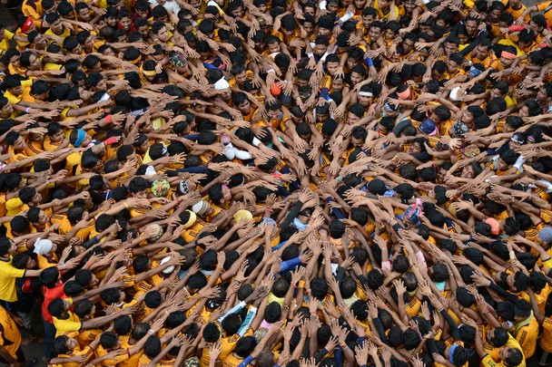 Young people in Mumbai, India press together to build a human pyramid to represent unity and to celebrate Janmashtami, a holiday honoring Krishna, the Hindu God of Love.  Devotees celebrate by fasting all day and staying up until midnight.